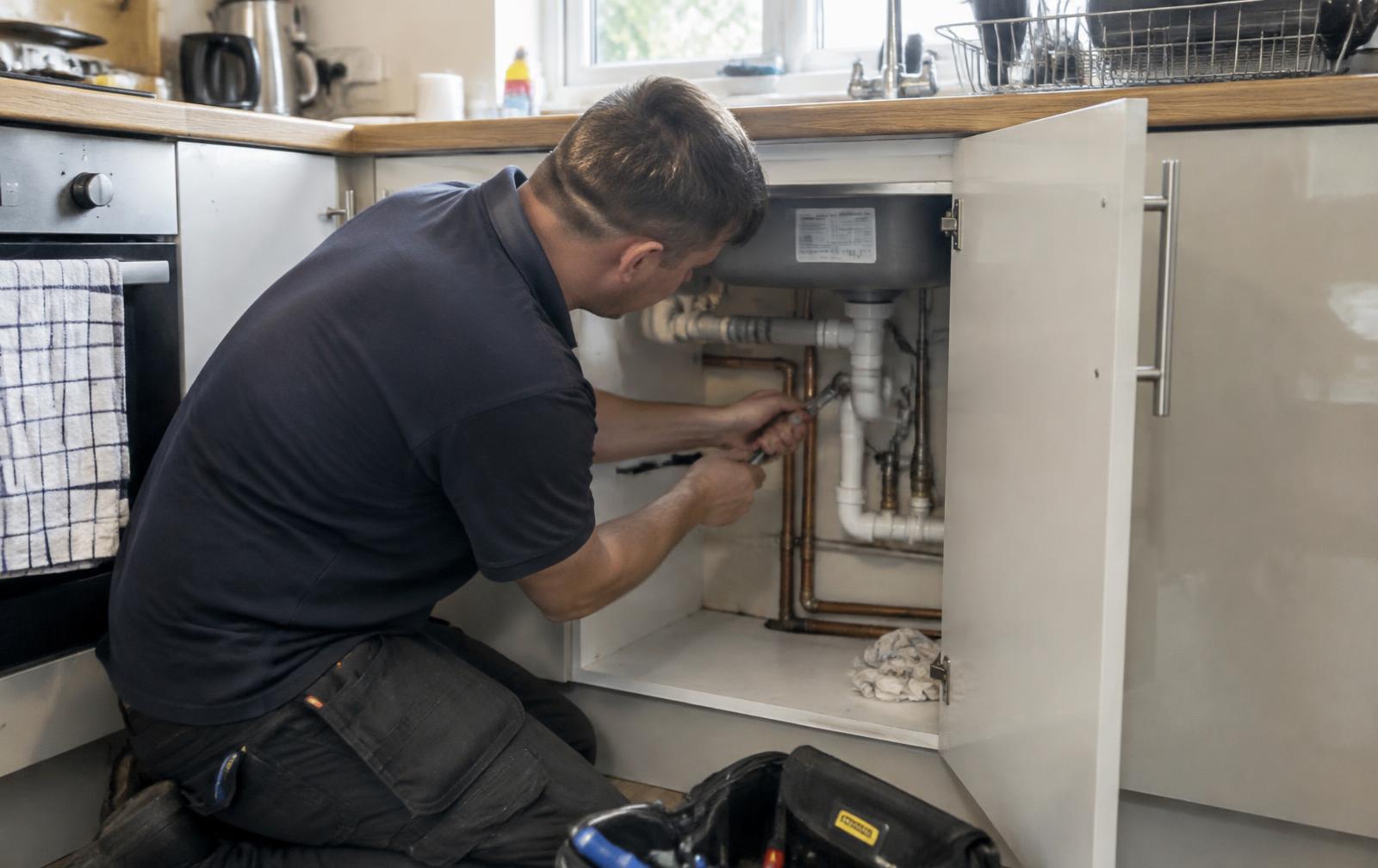 Plumber fitting pipework under a kitchen sink